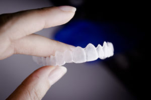 Close up of hand holding a top tray of invisalign clear aligners.